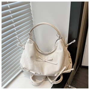 Detailed view of cream hobo bag featuring pleated texture and decorative bows