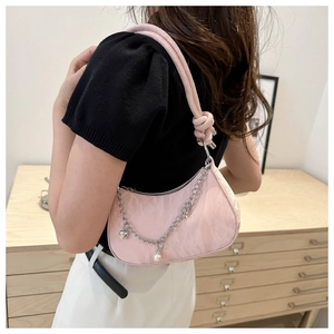 Detailed shot of pink hobo bag with silver chain and pearl charms worn by a model