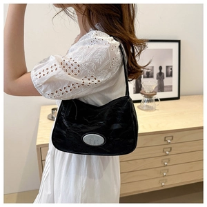 Detail of black pleated shoulder bag with silver metal plaque and smooth zipper texture