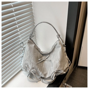 Detailed view of silver pleated fabric and decorative bow on the stylish shoulder bag