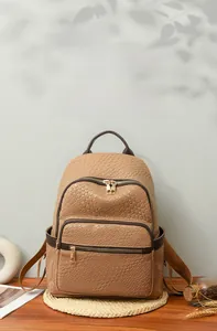 Detail of brown woven faux leather backpack with gold zippers on a rustic wooden stand