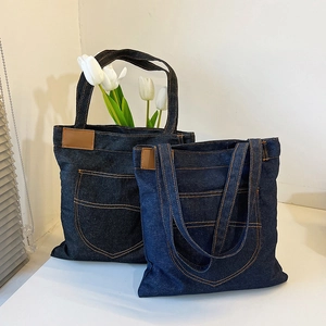 Denim canvas tote bag in dark and medium blue with orange stitching and large front pockets