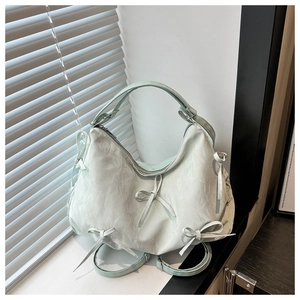 Detail of mint green pleated tote bag with bow accents and adjustable strap detail