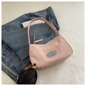 Detail of light pink shoulder bag with glossy pleated texture and silver logo plate