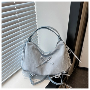 Detail of light blue pleated tote with decorative bows and adjustable shoulder strap