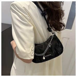 Detail of black wrinkled texture shoulder bag with silver chain and large pearl charm