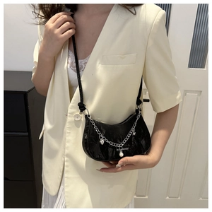 Detail of black crescent crossbody bag with silver heart chain and pearl charms