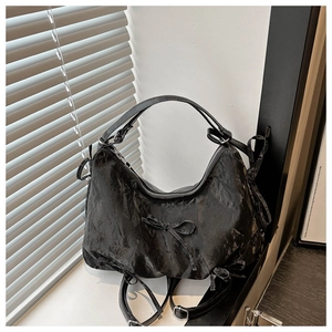 Detail of black pleated shoulder bag with decorative bow and secure silver zipper closure