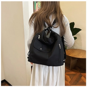 Rückansicht einer Person mit dem großen schwarzen Nylon-Rucksack für den täglichen Pendelverkehr