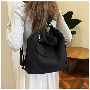 Rückansicht eines schwarzen Nylon-Rucksacks mit vielen Taschen, getragen von einem Modell