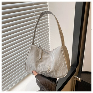Close-up of silver pleated texture shoulder bag with oval metal logo plate detail