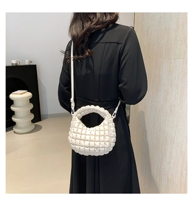 Detail of a creamy white popcorn textured mini tote bag with crossbody strap on model