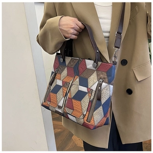 Detail view of colorful patchwork tote bag with zipper pockets and textured leather