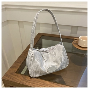 Detail of silver metallic crinkled texture underarm bag with an oval brand logo plaque
