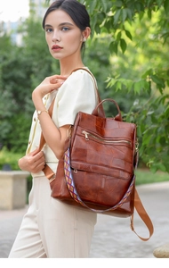 Detail of vintage brown patchwork PU leather backpack with colorful woven strap outdoors