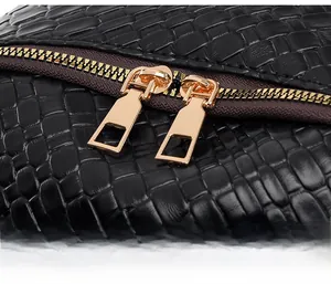 Detail of premium golden double zipper on black woven leather bag with smooth finish