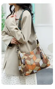 Detail of color-block tote bag featuring geometric patterns and a woven ethnic strap