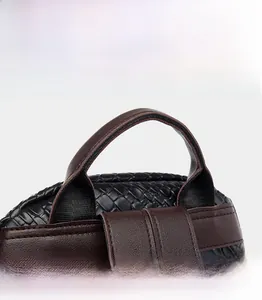 Detail of woven black bag featuring brown leather handle and intricate stitching