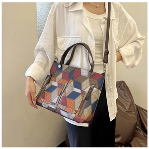 Detail of 3D geometric patchwork tote bag with vertical zippers and leather texture
