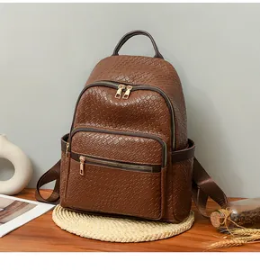 Close-up of dark brown woven leather backpack with gold zippers and side pocket detail