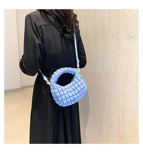 Detailed back view of a quilted sky blue mini tote bag worn with a crossbody strap