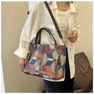 Detail of geometric pattern tote bag showing side zipper pockets and brown handle