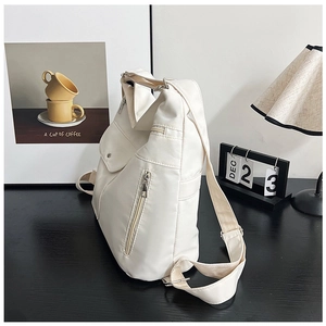 Nahaufnahme einer weißen Nylontasche mit Reißverschlusstaschen auf einem minimalistischen Tisch