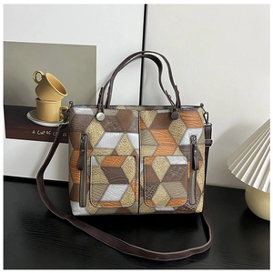 Detail of geometric patchwork leather tote bag with bronze zippers and dual handles