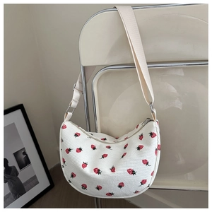 Detail der weißen Cord-Hobo-Bag mit Erdbeerdruck auf einem minimalistischen Stuhl
