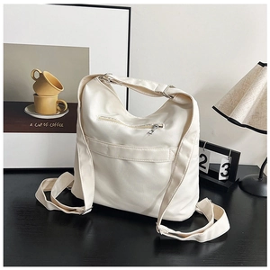 Detailansicht der cremefarbenen Nylontasche mit silbernem Reißverschluss und breitem Gurt