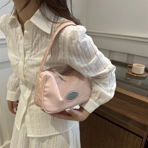 Pink niche underarm bag with landscape ripple texture shown on model in a cozy cafe