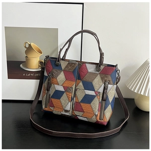Detail of 3D geometric patchwork tote bag featuring front zippers and textured faux leather
