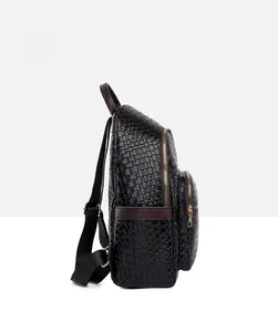 Side view of black woven texture backpack with brown leather trim and gold hardware