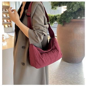Detail of burgundy quilted hobo bag with adjustable wide strap shown on a model