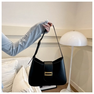 Detail of a black matte leather baguette bag with a gold buckle and adjustable strap