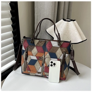Detailed view of geometric patchwork tote bag with 3D colorful pattern and zip accents