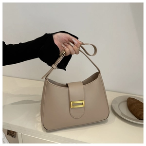 Detail of apricot faux leather baguette bag featuring a textured golden rectangular buckle