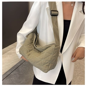 Detail of olive green quilted crossbody bag featuring large diamond stitch texture