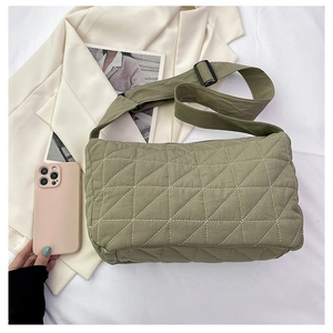 Detail of green quilted crossbody bag showing nylon texture and triangle stitching