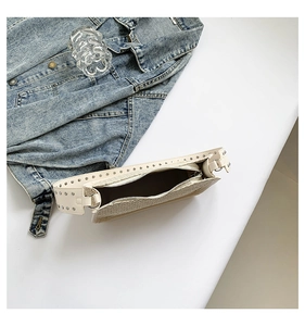 Détail du sac tressé avec fermeture éclair, bandoulière cloutée et veste en jean