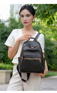Detail of black woven leather backpack showing golden zippers and textured snake-embossed material