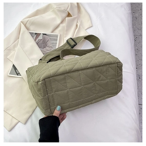 Close-up of olive green quilted dumpling bag with geometric stitching and adjustable strap