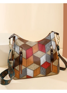 Close-up of geometric leather patchwork tote with ethnic embroidery strap and gold rings