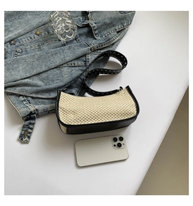 Vue à plat d'un sac d'épaule en paille tressée avec bordure en cuir noir et rivets argent