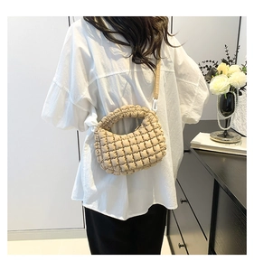 Beige quilted cloud tote bag with wide strap shown worn by a model in a cozy home setting