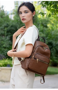 Detail of vintage brown leather backpack with woven texture and gold zipper outdoors