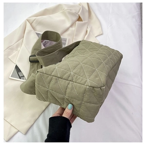 Detailed macro view of olive green quilted crossbody bag with diamond stitch and wide strap