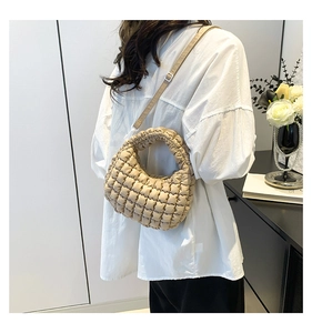 Detail of a beige bubble textured mini tote bag with slim shoulder strap worn by model