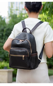 Outdoor lifestyle view of black woven texture backpack with brown leather trim and gold zippers