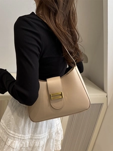 Stylish beige baguette bag with gold metal buckle shown on a model in a minimalist setting